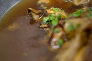 Nærbillede af velsmagende oksekødsuppe med champignoner og frisk persille, ideel til kulinarisk blog.