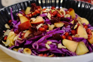 Farverig salatskål med rødkål, æbler, nødder og granatæble - sund vegetarisk ret