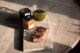 Træskærebræt med en steak skåret i skriver, med dressinger ved siden af