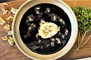 GRå skål med mørk hyldebærsuppe og hvid creme på toppen