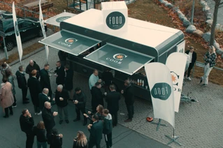 Mennesker samles ved en mobil madbod fra COOK ved en udendørs networking event.