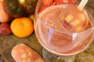 Stor glas skål med lyserrød juice og grøntsager i baggrunden