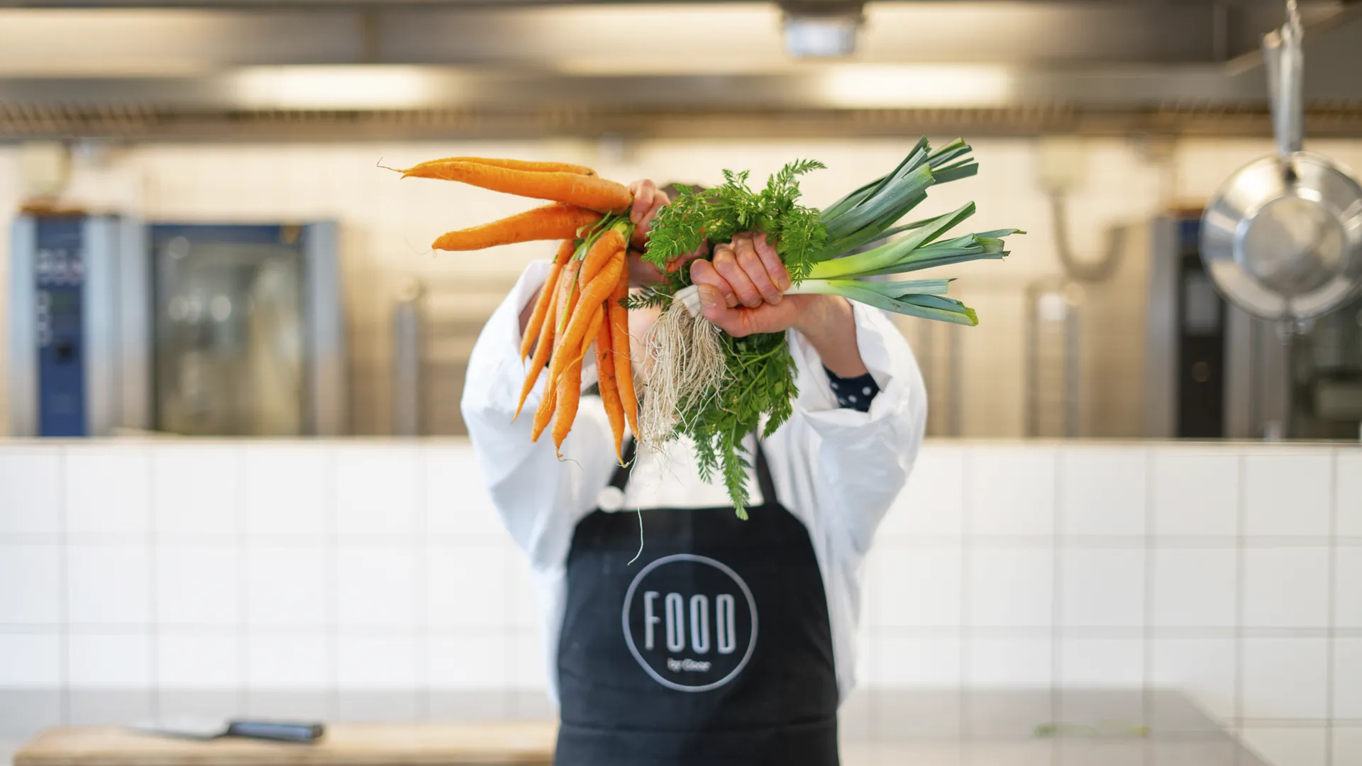 Friske ingredienser til madlavning med tomater, løg, citron, hvidløg, basilikum, salt og kniv på sort baggrund.