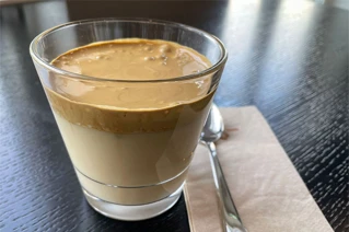 Et enkelt glas med kaffe og karamel skum på et sort bord