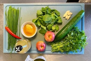 Skærebræt med æbler, agurk, chili og mange andre grøntsager