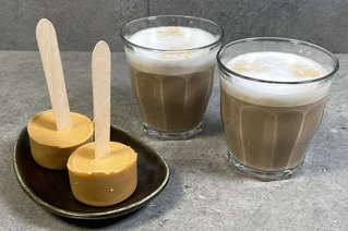 To glas med kaffe ved siden af to stænger med karamel