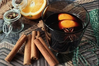 Kanelsstænger og et glas med gløgg og appelsinskiver
