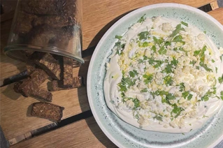 Hvid skål med fetadip og grønt pynt på toppen